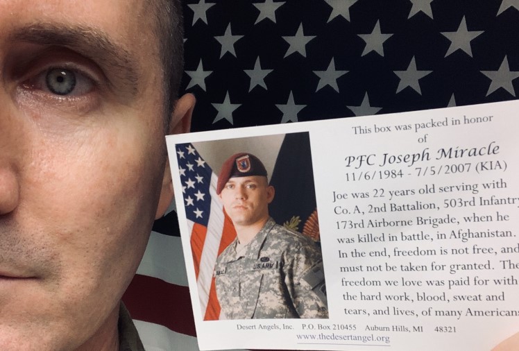 Soldier holds post card packed into the desert angels box.
