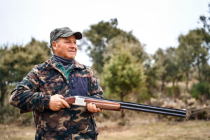 Senior man with shotgun hunting in countryside - senior rifle