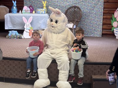 The Easter Bunny at OCSCs Easter Egg Hunt poses with two brothers for a photo